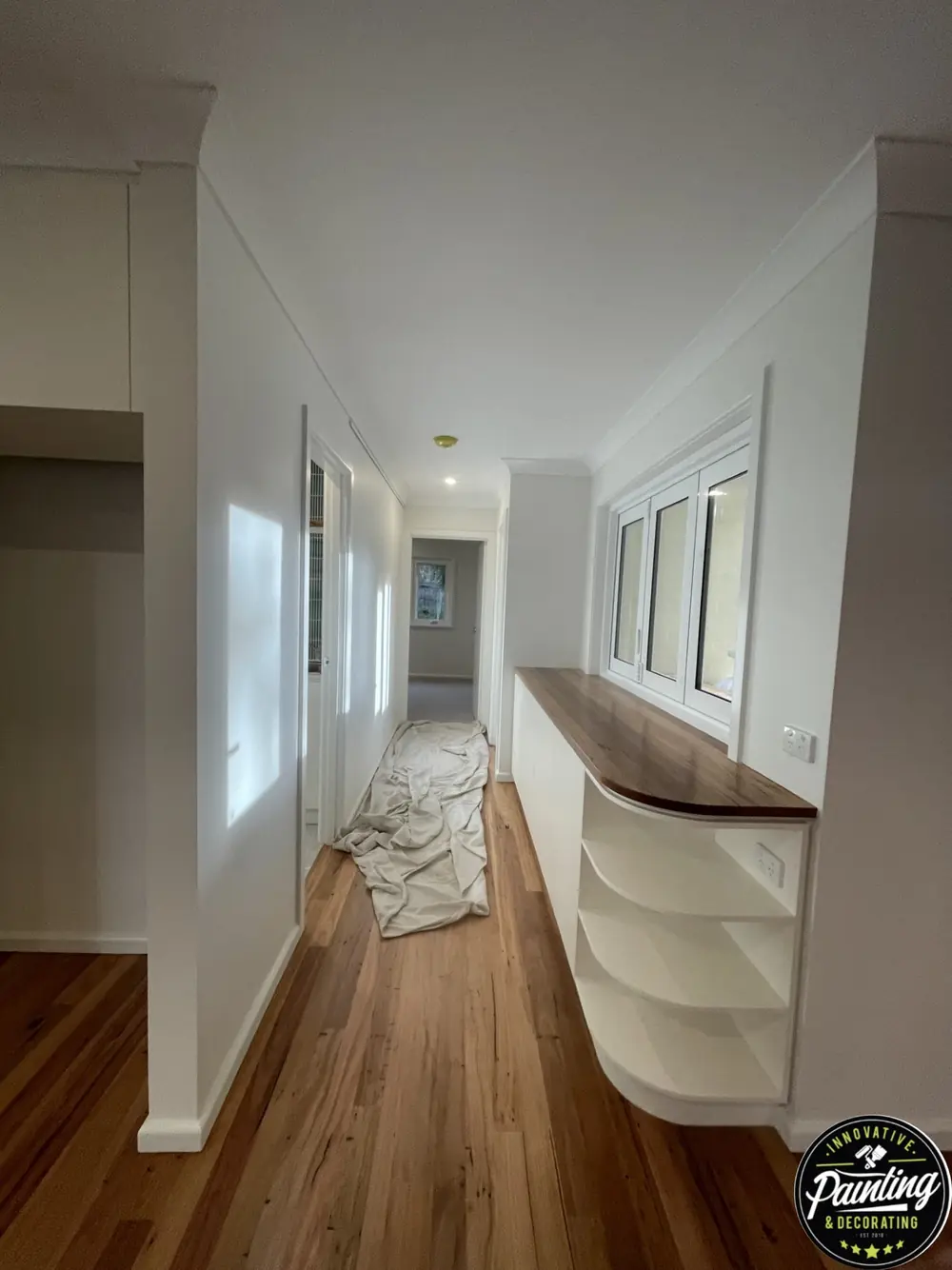 Freshly painted hallway with bright white walls and timber flooring