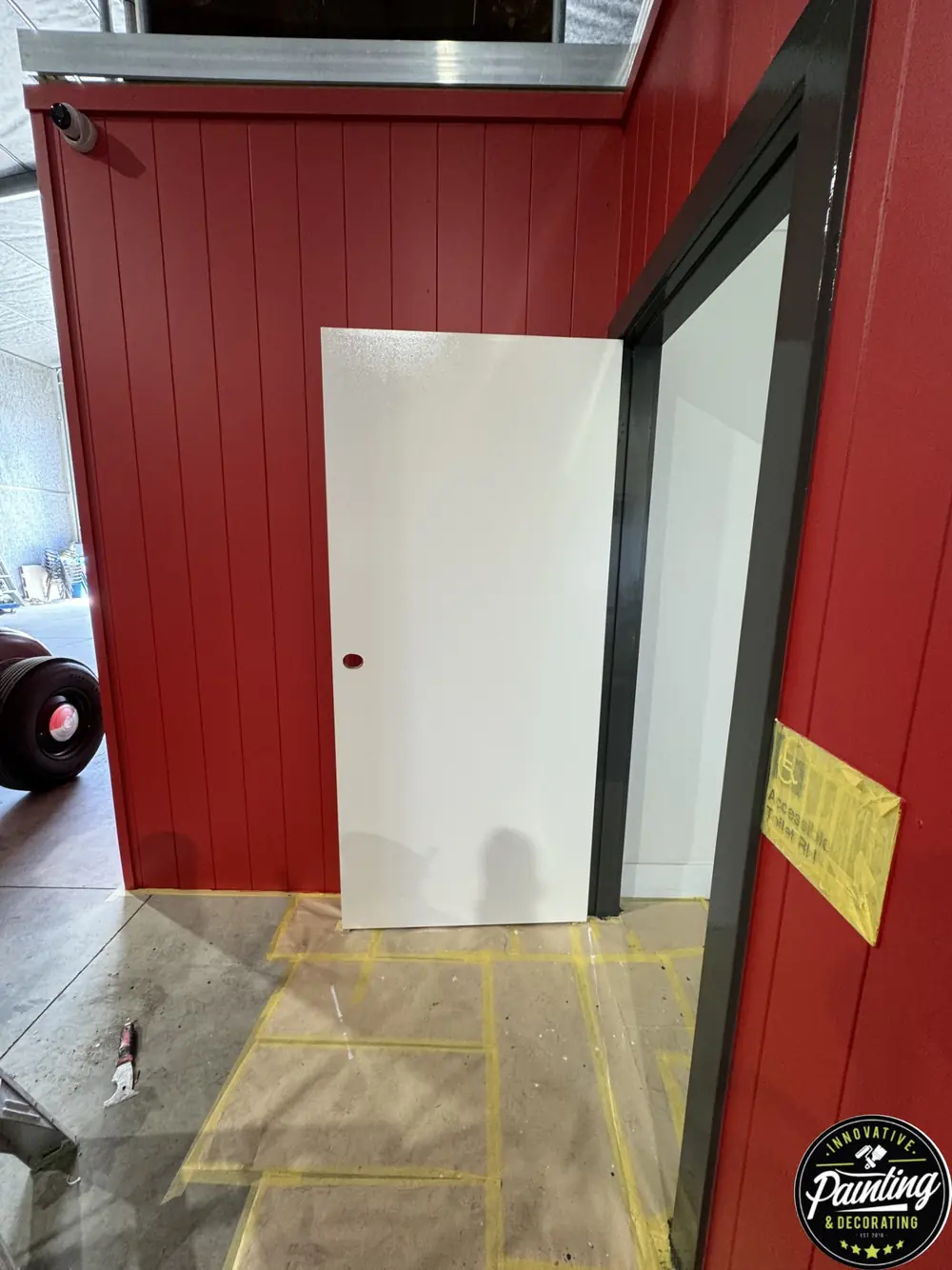 Freshly painted red commercial wall beside a white door and protected floor