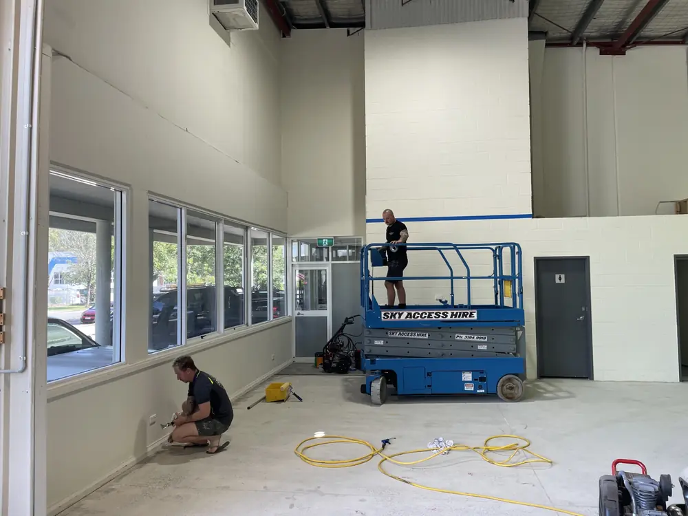 Two painters preparing and painting a large commercial interior using a scissor lift