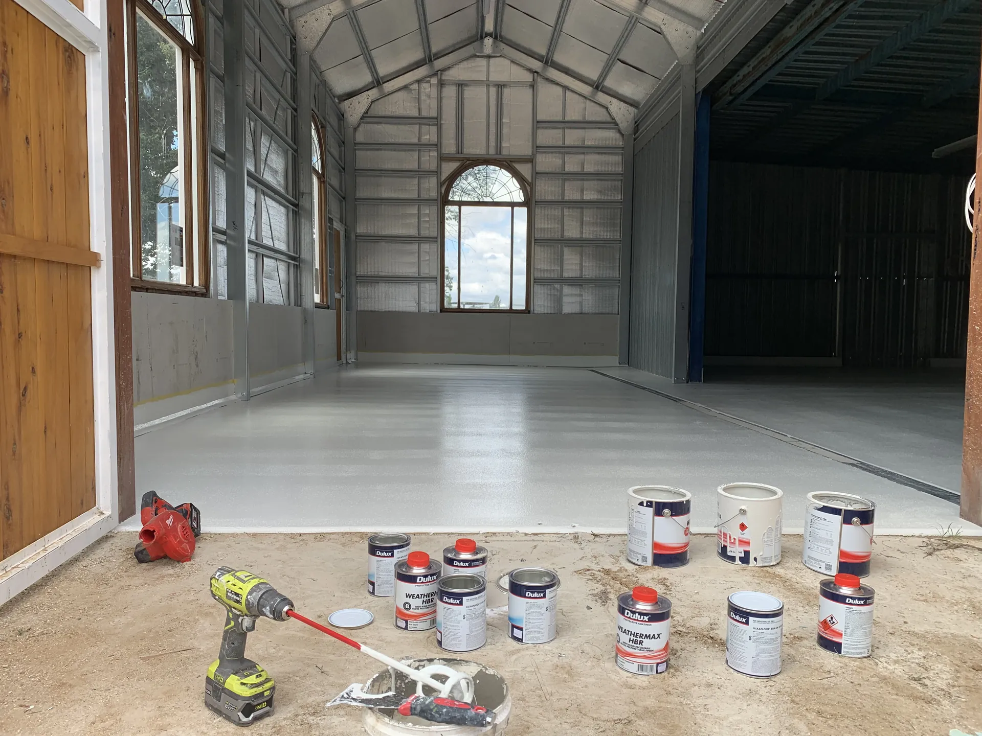 Workshop floor prepared for an epoxy coating with paint tins and tools ready