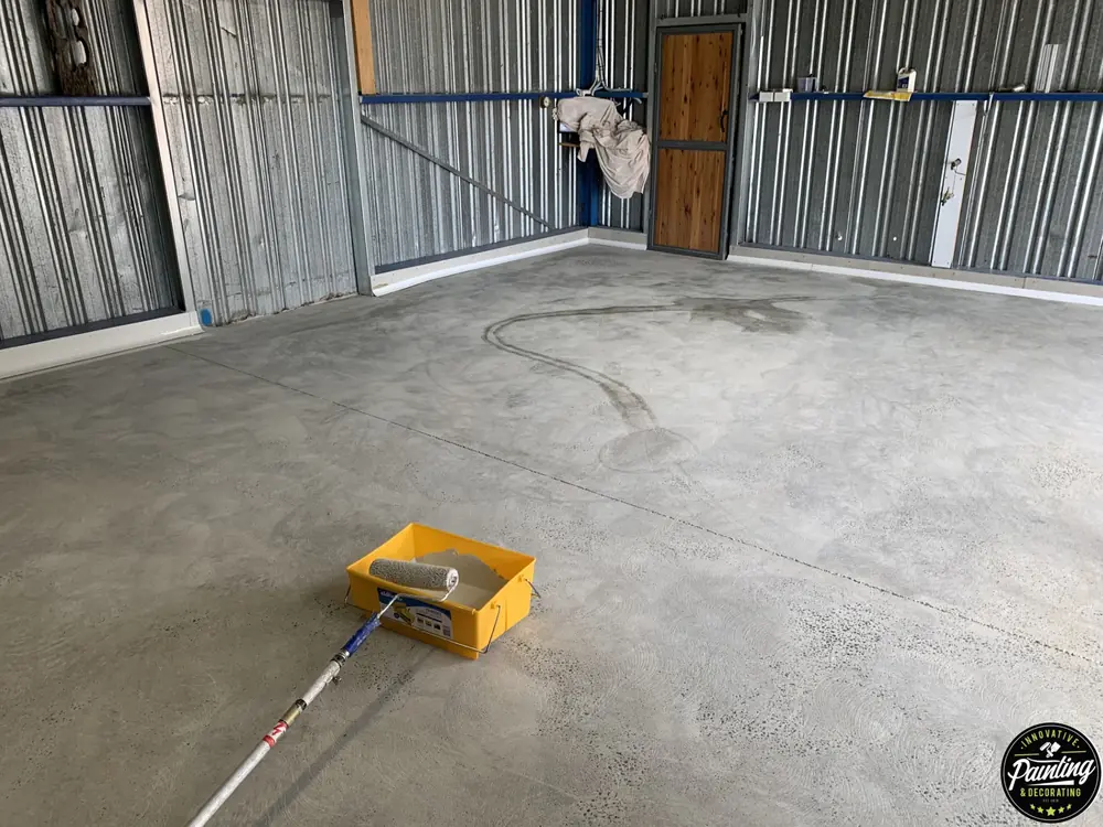 Concrete workshop floor during preparation with coating tools on the surface