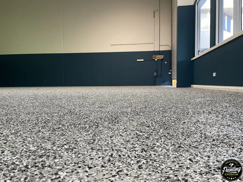 Finished speckled epoxy floor beneath dark blue workshop walls