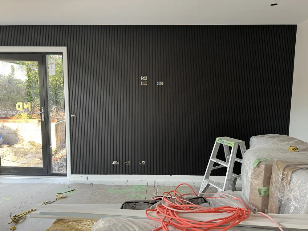 Finished interior room with a dark feature wall beside large glass doors
