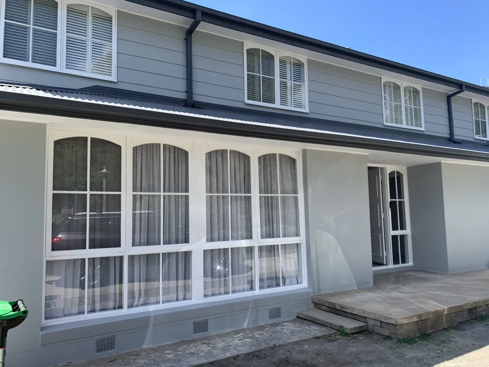 Freshly painted grey two-storey exterior with white arched windows
