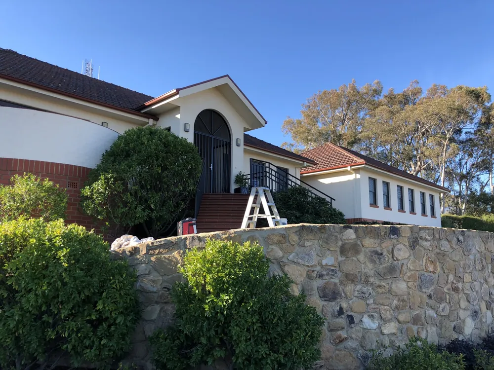 Freshly painted home exterior with a red tiled roof and stone retaining wall