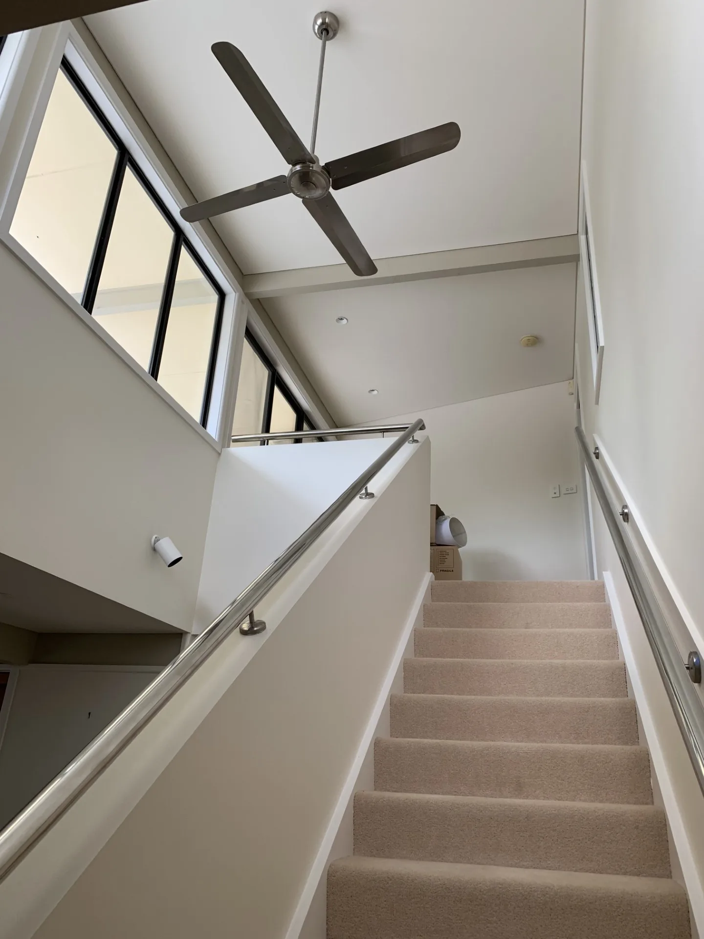 Bright freshly painted stairwell with white walls, high ceiling and dark window frames