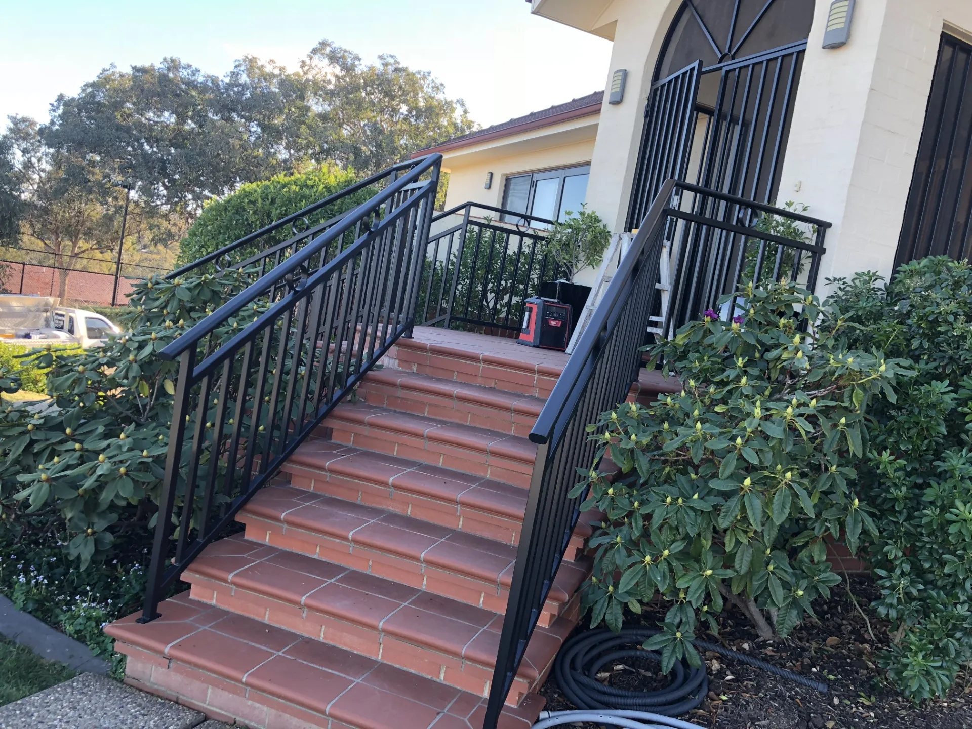 Painted exterior stairway with dark railings and warm timber steps