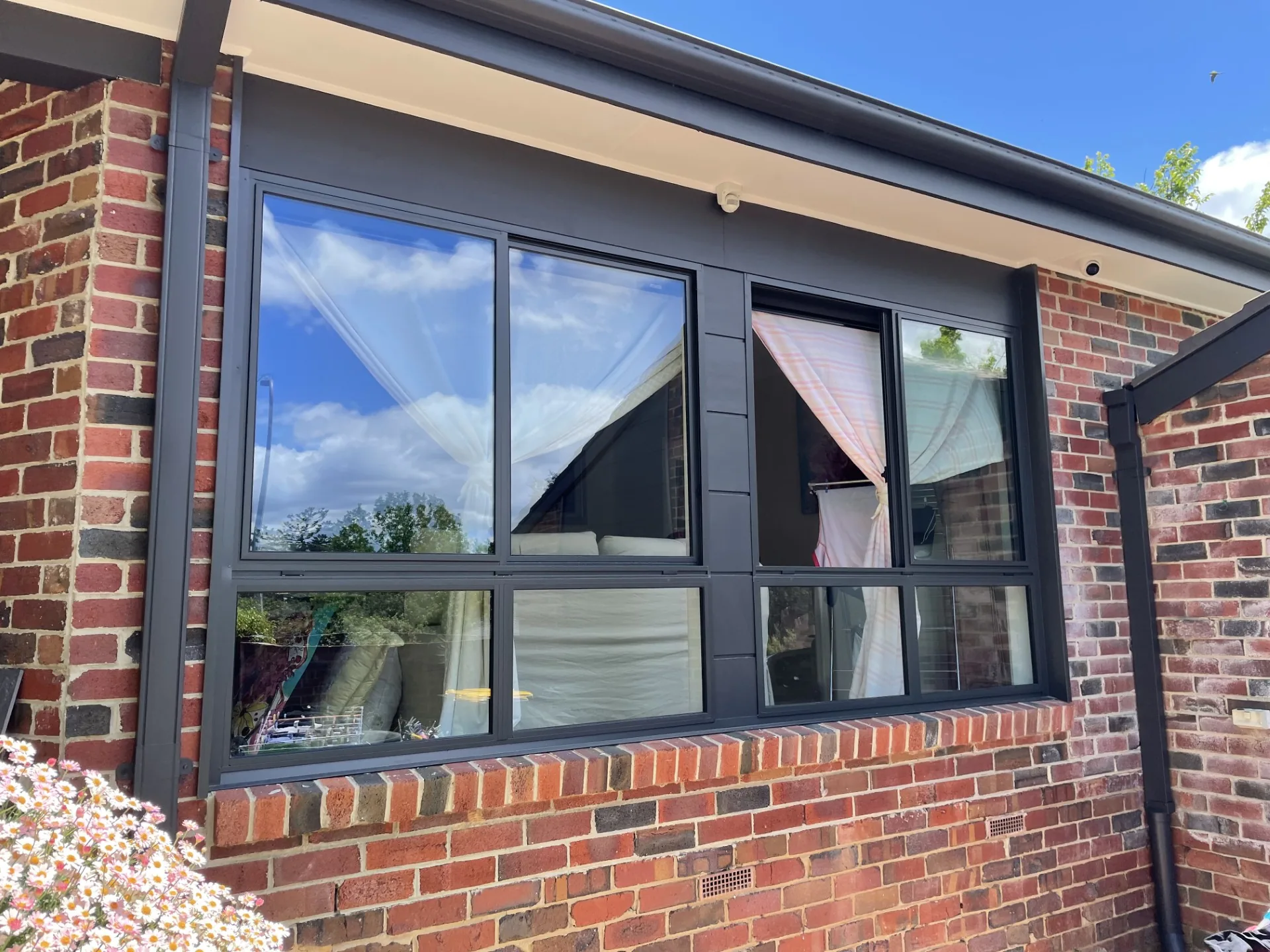 Freshly painted dark window frames on a brick home exterior
