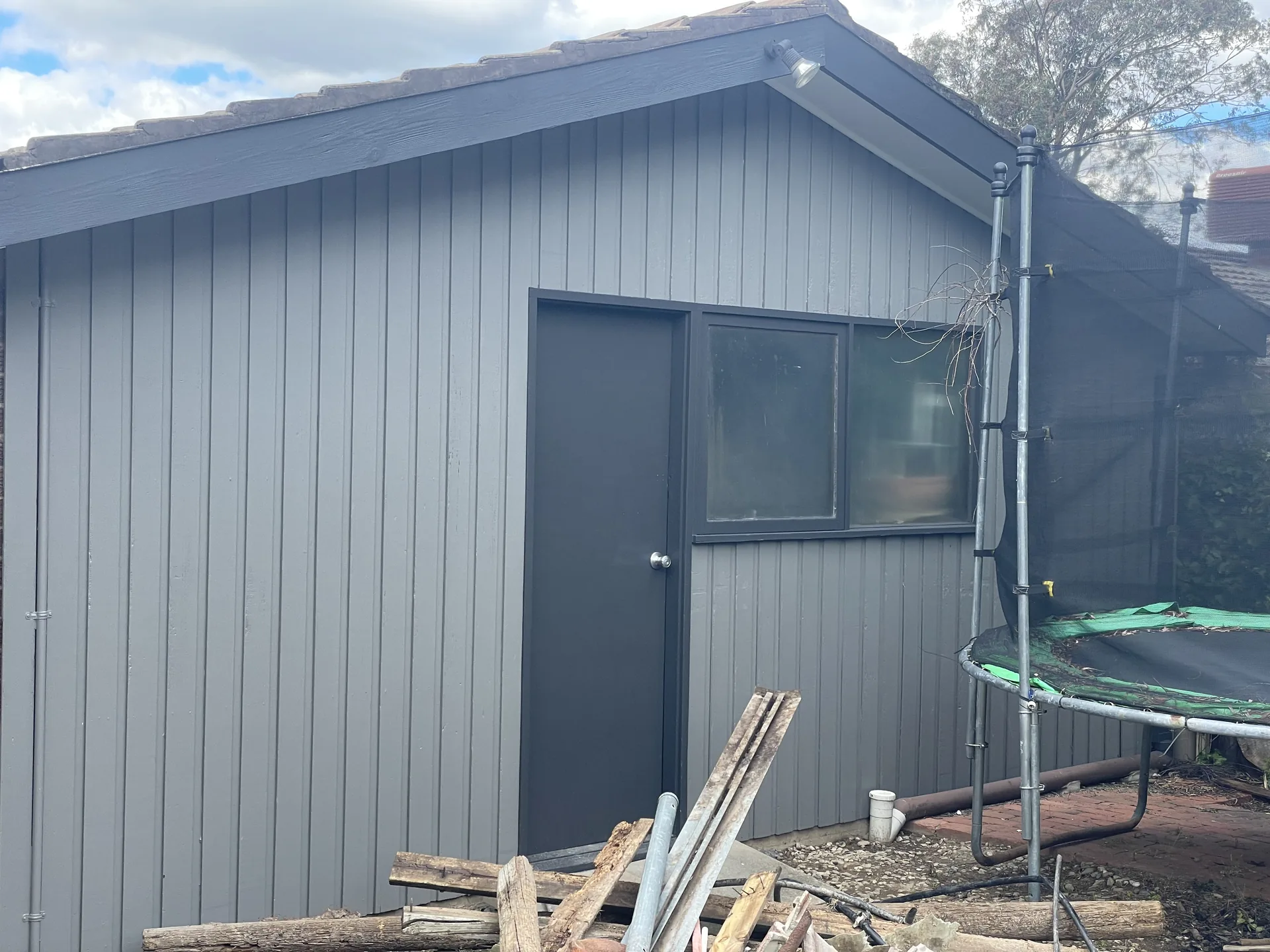 Freshly painted dark exterior cladding on a residential outbuilding