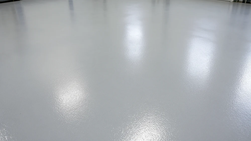Close-up of a light-grey epoxy floor with a bright circular reflection
