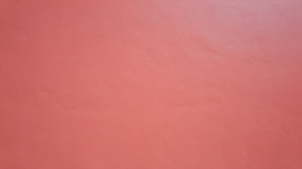 Close-up of a freshly painted coral-pink wall with subtle surface texture