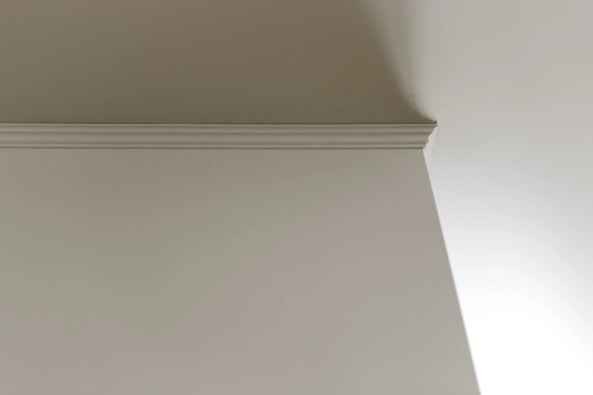 Freshly painted warm neutral interior walls meeting a white ceiling and cornice